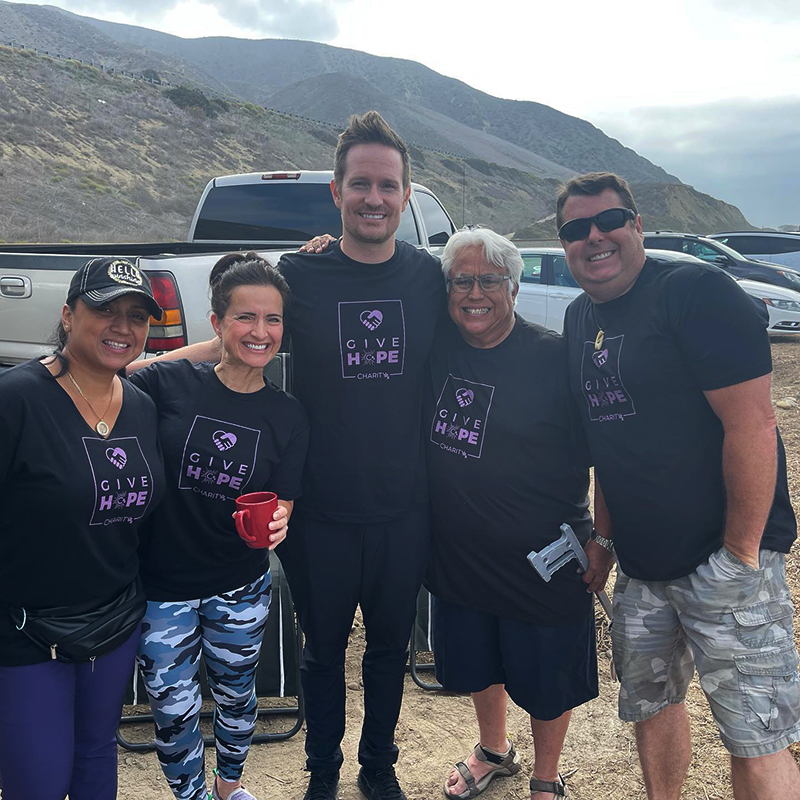 A group of volunteers poses in front of vehicles at the beach