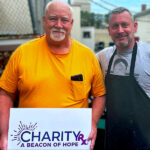 Joe Maxon holds a CharityRx sign while he volunteers for Open Door Mission