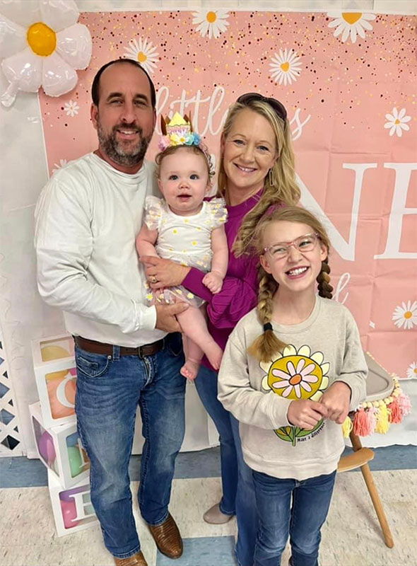 Meet CharityRx Rep Tonya Saucer - A smiling man, woman, young girl and a baby girl stand closely in front of a pink backdrop together