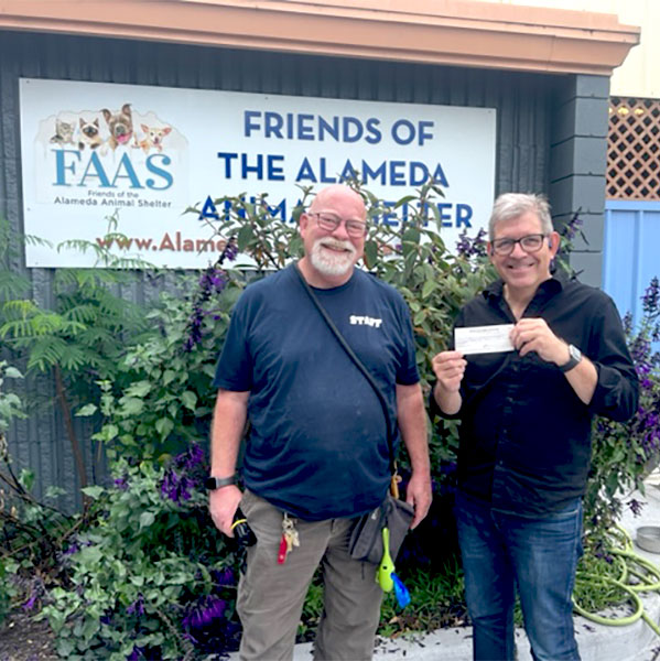 CharityRx Reps Rescue Shelter Pets with Donations. Two middle-aged men stand smiling in front of the Friends of the Alameda Animal Shelter facility. The man on the right is holding a check.