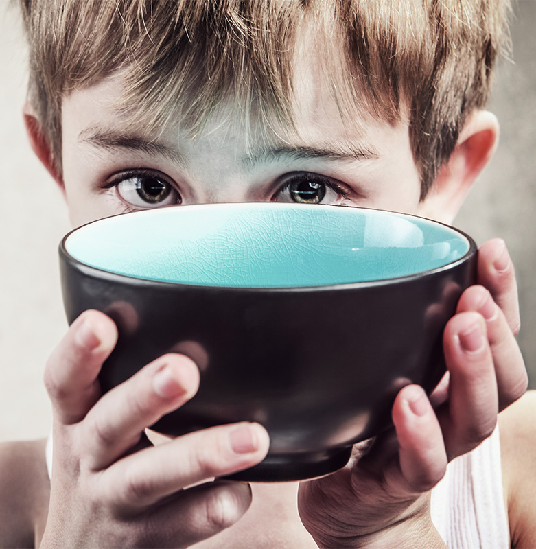 CharityRx helping to reduce food insecurity in America with Feeding Youth USA. Young boy holding an empty bowl at eye level