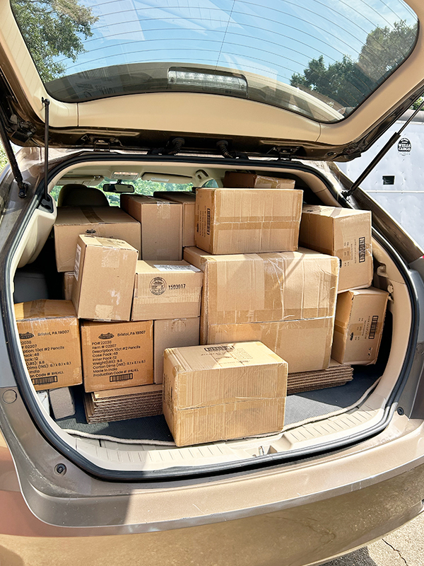 Image: The compartment of a hatchback vehicle is filled to the top with boxes of different sizes.
