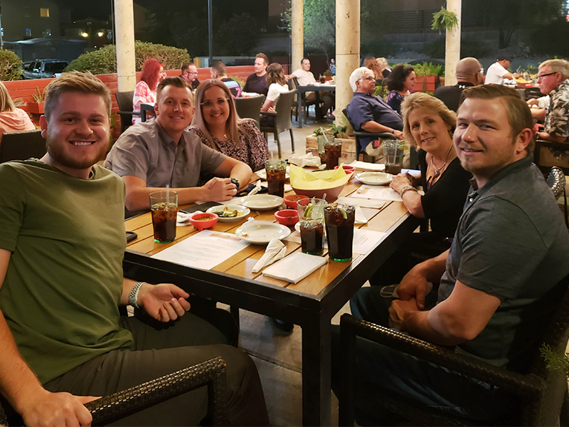 Meet CharityRx Rep David Gingrass. Image: Three men and two women sit around a table in a restaurant. They are all looking into the camera and smiling.