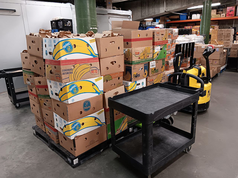 CharityRx Founder's Day 2023: The Power of Giving Back. Image: A large stack of approximately 40 boxes full of food are stacked inside a warehouse.