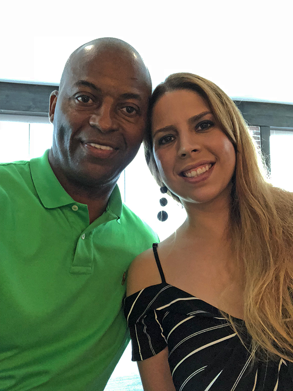 Image: A black man and a Latina woman sit with heads leaned together, smiling at the camera. CharityRx Rep, Ronald Kellogg