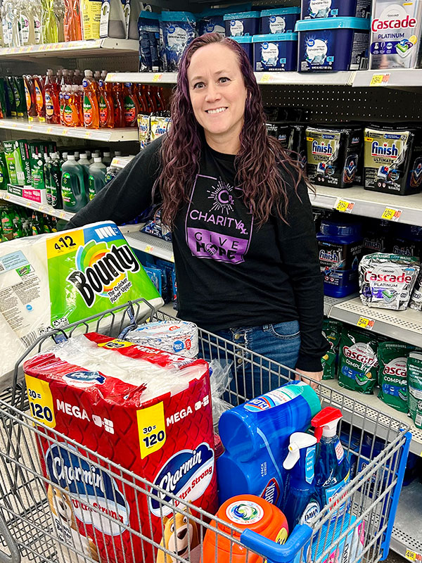 Image of a woman standing next to a shopping cart full of household items.