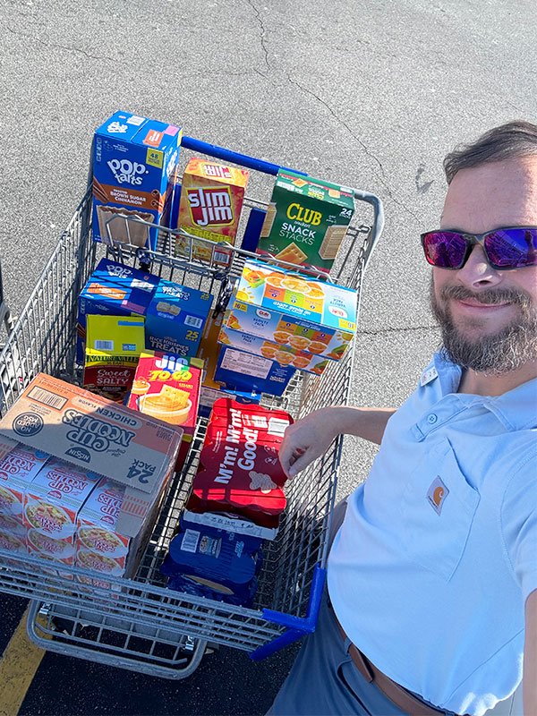 Image of a man next to a shopping cart full of food to be donated to Run 5 Feed 5.