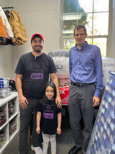 Image of a man, his young daughter, and a representative of In My Shoes organization. CharityRx Supports Women and Children