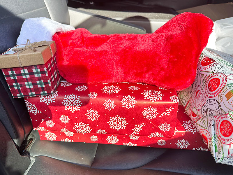 Images of wrapped gifts and a Christmas stocking on the seat of a car. CharityRx Spreading Hope Through Donations
