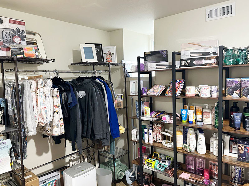 Image of a room with shelves and racks stocked with clothing, household items, and personal care products.