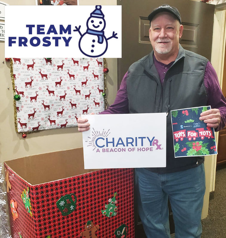 Image of an older man next to a Toys For Tots donation bin holding a CharityRx sign.