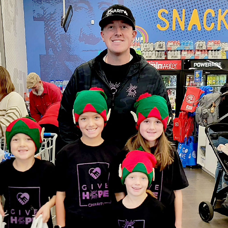 Image of a smiling man and four children standing at the checkout in a store.