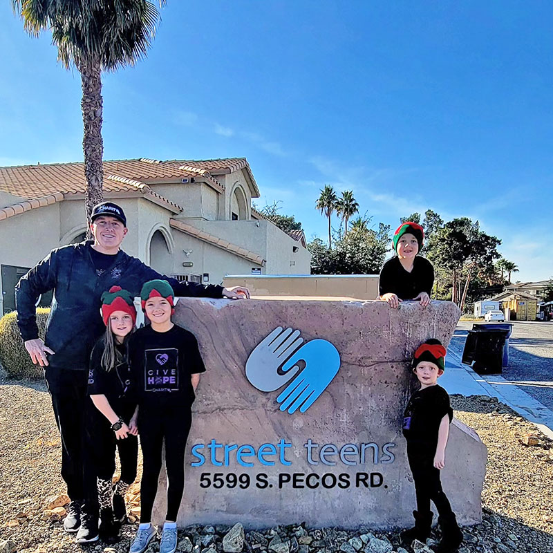 Image of a man and four children standing outside in front of a Street Teens sign.