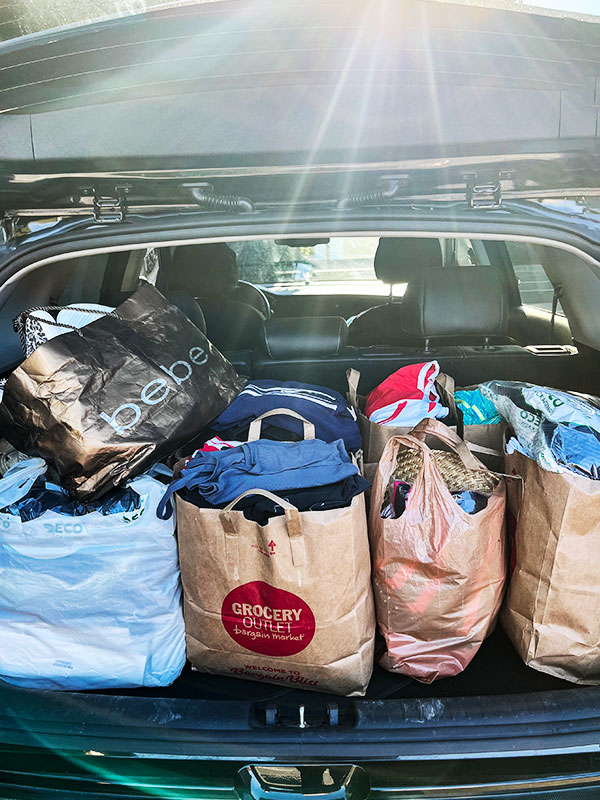 Image of a car trunk full of bags of clothing to be donated.