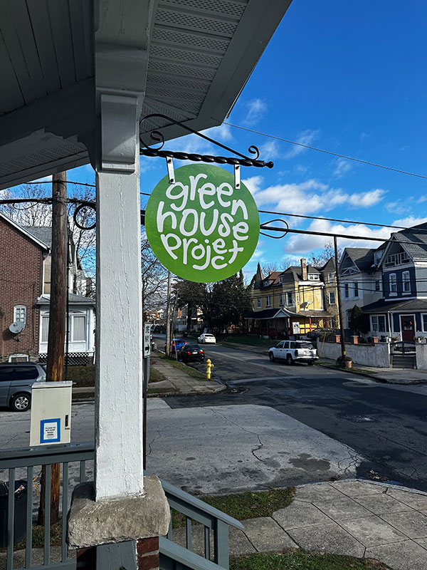 Image of the Greenhouse Project sign on a porch post.